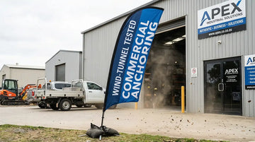 Heavy double-sided industrial feather flag installed at a windy commercial site