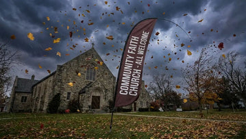 Heavy duty church feather flag flexing gracefully against late autumn windstorm on church lawn