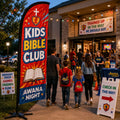 Awana Night Kids Bible Club church feather flag outside a church entrance with children, parents, and volunteers arriving