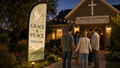 Grace and Peace church feather flag with dove design near a peaceful church garden entrance