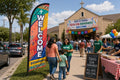 Church feather flag Hispanic / Bilingual Ministry placed roadside 500ft before entrance visible to Sunday traffic