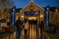 Two Christmas Advent church feather flags flanking main entrance with greeters and families arriving