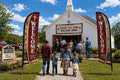 Two Rural / Country Church church feather flags flanking main entrance with greeters and families arriving
