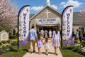 Two Easter / Spring church feather flags flanking main entrance with greeters and families arriving