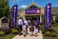 Two praise and worship church feather flags flanking main entrance with greeters and families arriving