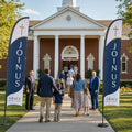 two join us church feather flags flanking main entrance of brick Baptist church with greeters and families arriving