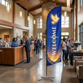 Welcome church feather flag on indoor cross-base stand in modern church lobby with welcome desk and coffee station
