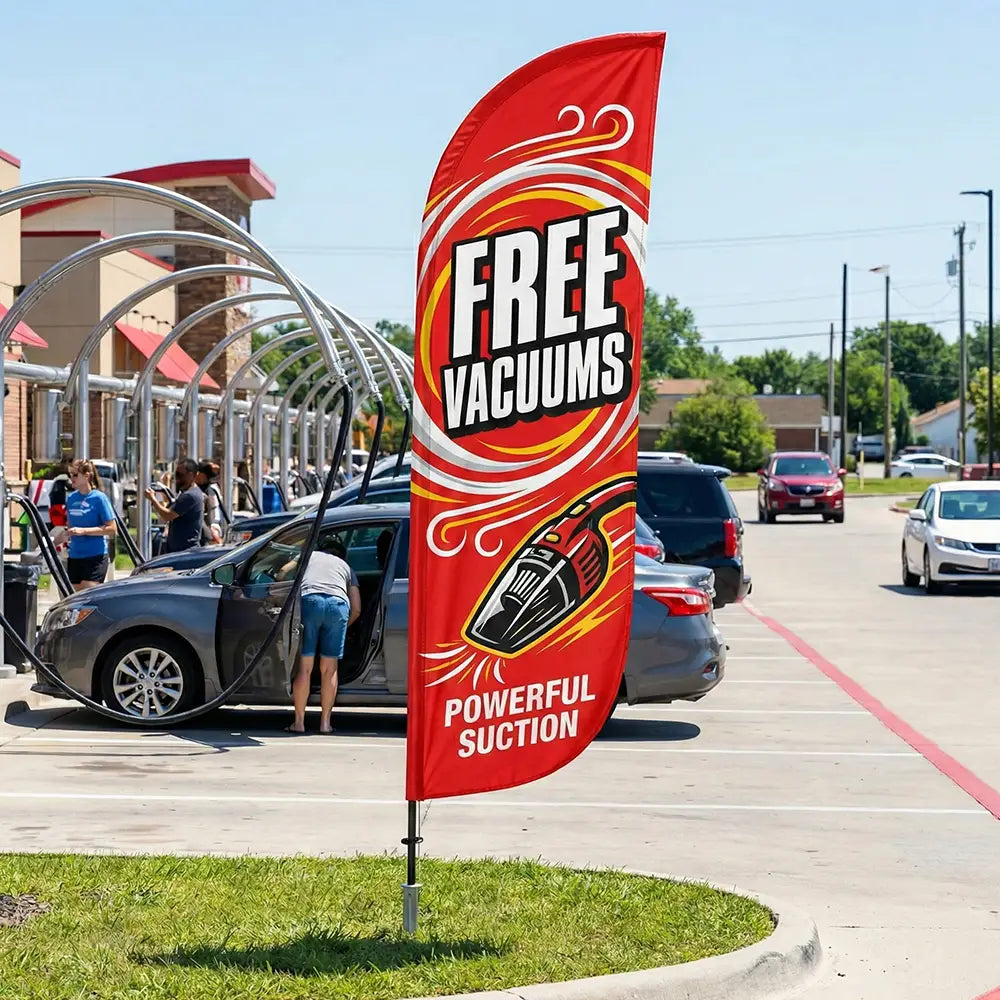 Bold red Free Vacuums feather flag positioned to attract drive-by traffic to a car wash facility.
