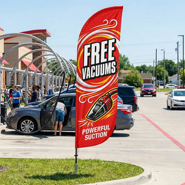 Bold red Free Vacuums feather flag positioned to attract drive-by traffic to a car wash facility.
