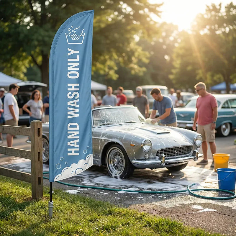 Artisanal "Hand Wash Only" feather flag with blue and white soap graphics, standing near a classic car being washed by hand.