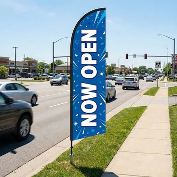 High-contrast blue and white Now Open feather flag positioned along a busy commercial corridor to capture drive-by traffic.