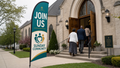 Join Us community church feather flag near a traditional church entrance