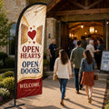 Open Hearts Open Doors church feather flag displayed beside open church doors with guests arriving