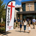 Red cross church feather flag with welcome message on a concrete church entrance plaza