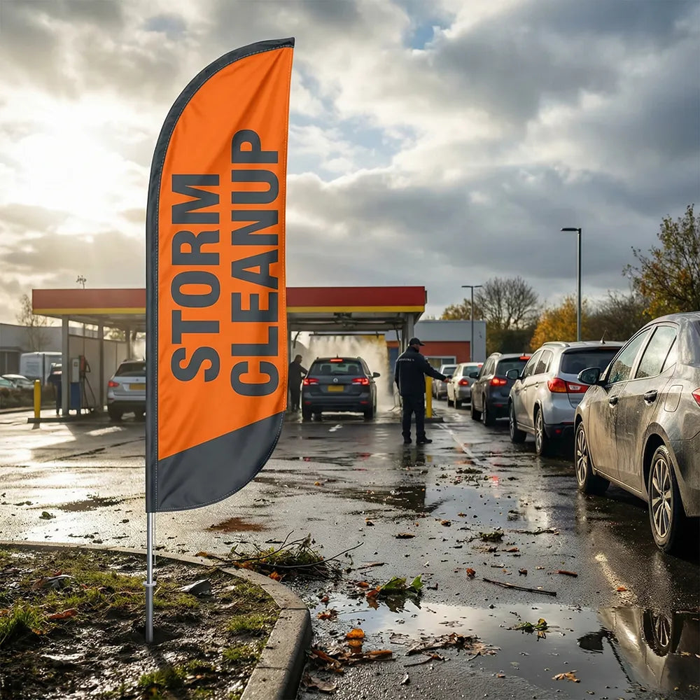 Safety orange Storm Cleanup feather flag positioned at a car wash entrance following a major rain event.