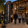 Young Adults Fellowship church feather flag in a modern church courtyard with young adults socializing