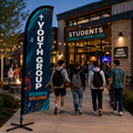Youth group church feather flag outside a student ministry center with teenagers and youth leaders arriving